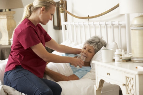 caregiver assisting an elderly woman on drinking water